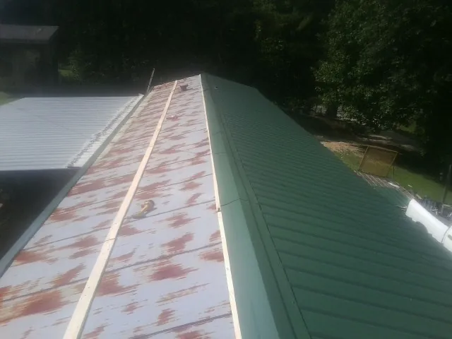 Old rusted panels beside newly installed green metal roofing — Wind Damage Roof Repair by Roofing Brothers in Turin