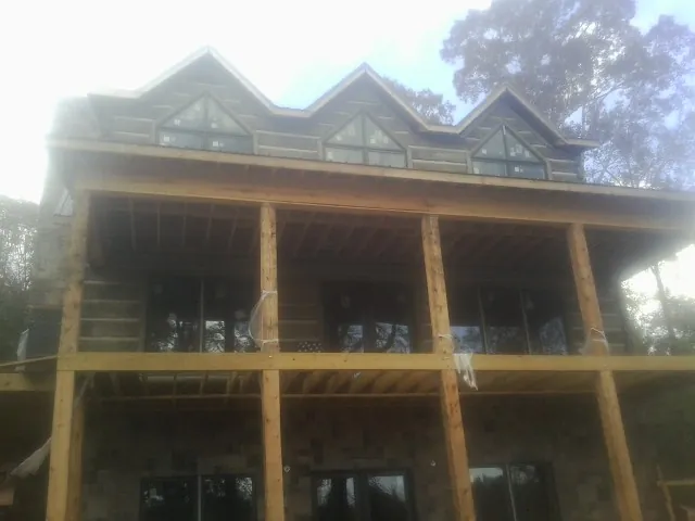 Dormers and porch framing on a large log home under construction — Roof Coating work by our crew in Turin