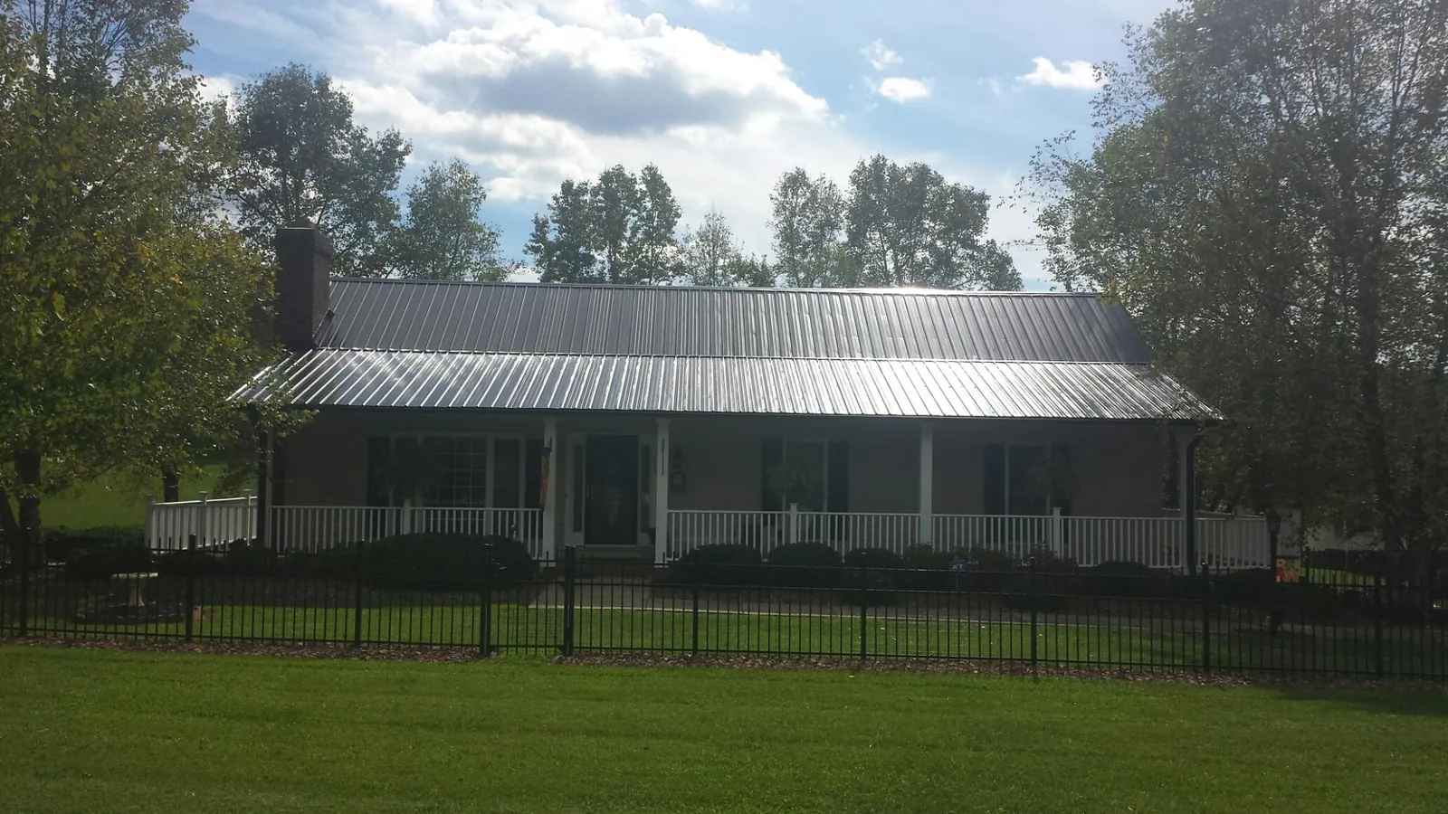 Gray metal roof on a brick ranch with a full width front porch — Gutter Guard Installation work by our crew in Turin
