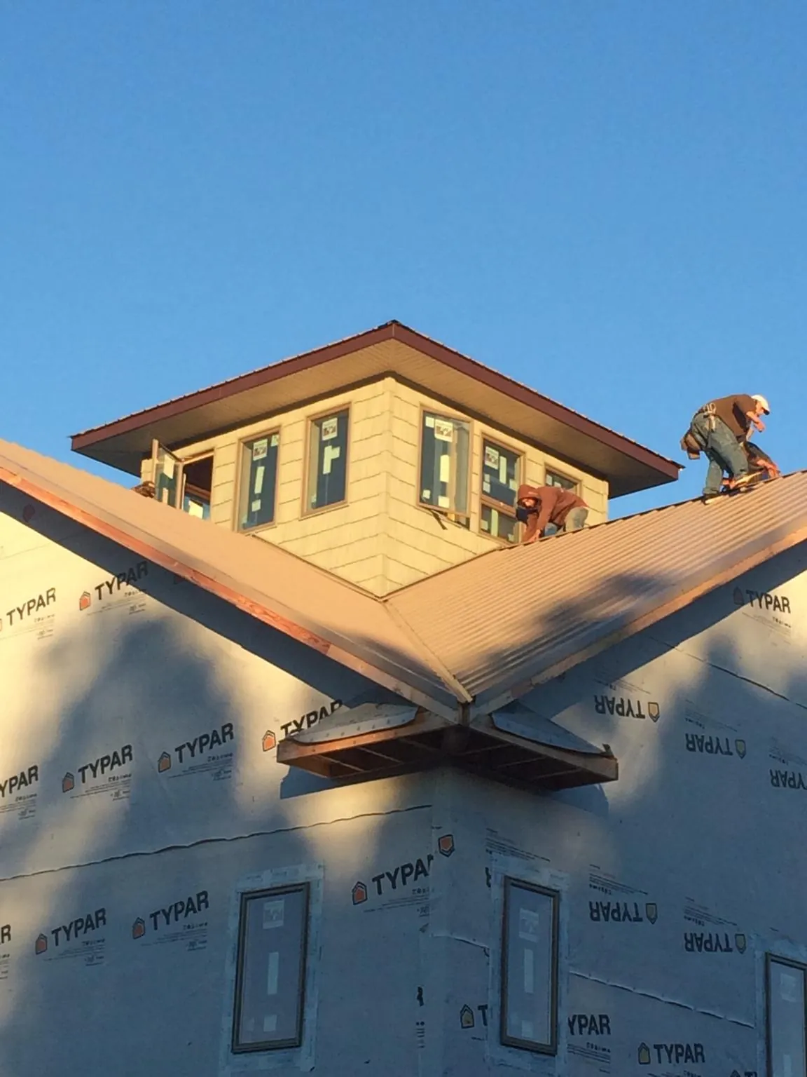 Roofers working around a rooftop cupola on a new metal roof at sunset — Roof Waterproofing in Turin by Roofing Brothers